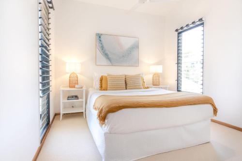 a white bedroom with a large bed and a window at Coastal Getaway Across From Dicky Beach in Caloundra