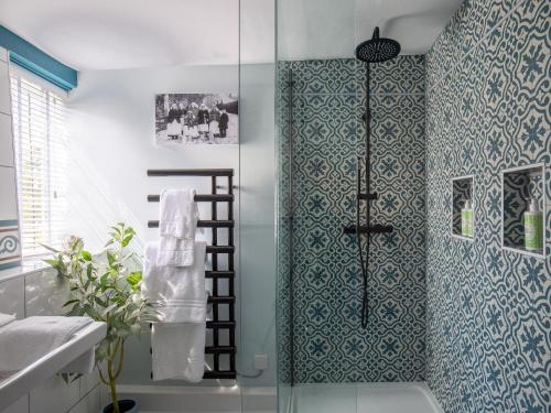 a bathroom with a shower with blue and white tiles at Locke's Cottage in Alderminster
