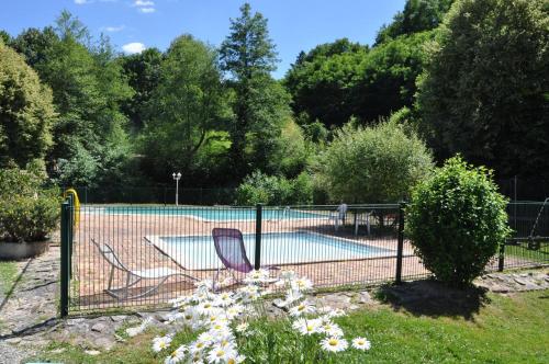 a fence with two chairs next to a swimming pool at Les Chalets Du Moulin Du Châtain 3 in Payzac