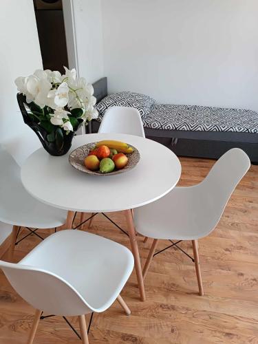uma mesa branca com um prato de frutas e um vaso de flores em Apartament fabryczny Comfort em Pisz