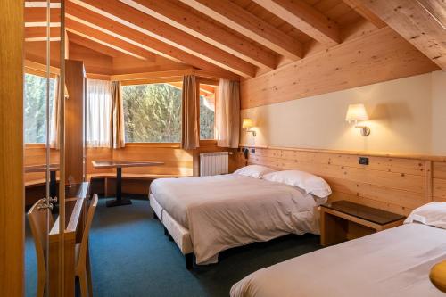 a room with two beds and a desk in a cabin at Hotel Garni Pegrà in Ponte di Legno