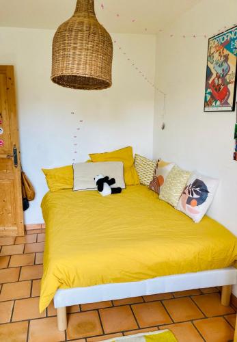 a bed with a yellow blanket and pillows on it at Villa avec piscine à Fuveau in Fuveau