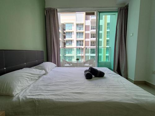 a bed with a pair of shoes on it with a window at Pacific Place Ara Damansara LRT Pool Parking Kitchen By Kenangan Homes in Petaling Jaya