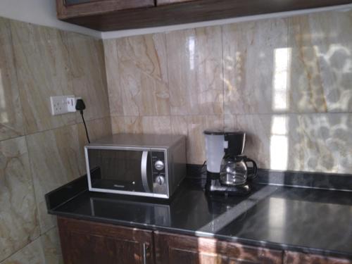 a microwave sitting on a counter in a kitchen at Modern 2 BR home w/ 3 ACs, 2 TVs near the beach in Dar es Salaam