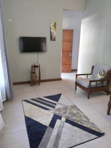 a living room with a tv and a chair and a rug at Modern 2 BR home w/ 3 ACs, 2 TVs near the beach in Dar es Salaam