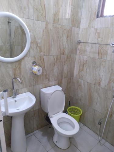 a bathroom with a toilet and a sink and a shower at Modern 2 BR home w/ 3 ACs, 2 TVs near the beach in Dar es Salaam