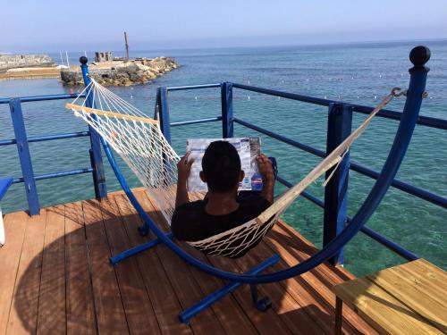 a man reading a book in a hammock on a boat at Manolya Hotel in Kérynia