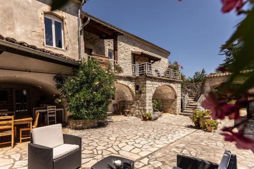 a stone courtyard with a building with a table and chairs at les monteils in Grospierres