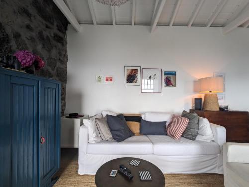 a living room with a white couch and a table at Casas do Horizonte in Ribeiras