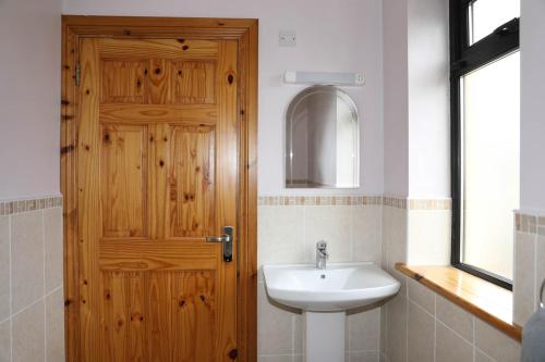 a bathroom with a sink and a wooden door at Narrow water house in Dundalk