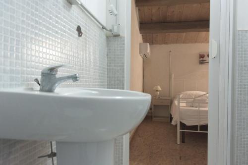 a bathroom with a white sink and a bedroom at Il Casale Suite&Rooms in Burgio