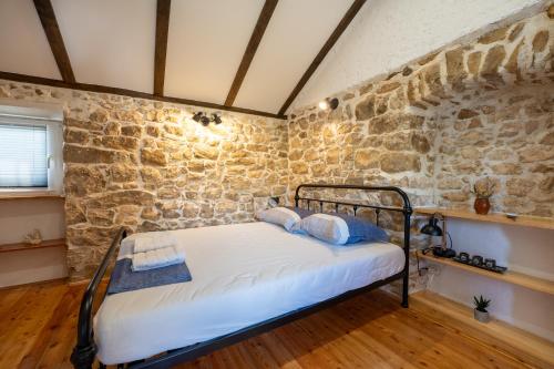 1 dormitorio con 1 cama en una pared de piedra en Kuća za odmor Nikola en Zadar