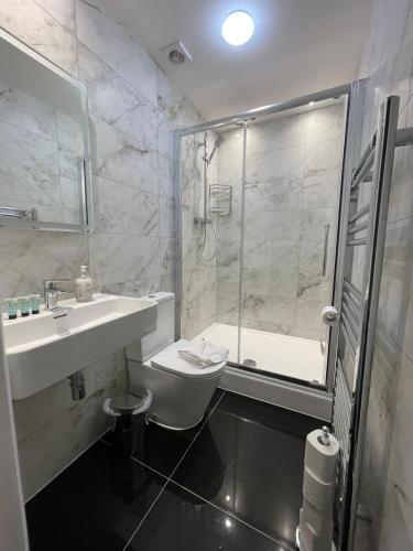 a bathroom with a toilet and a sink and a shower at Acacia Hotel in London