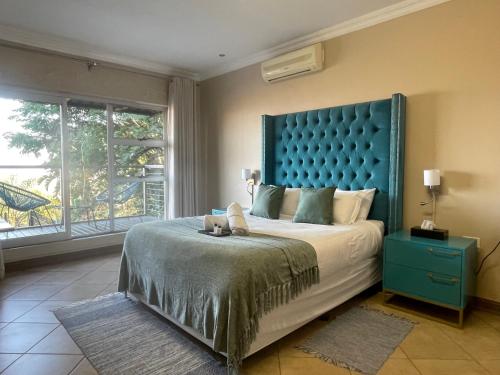 Un dormitorio con una cama grande con cabecero azul. en Boat Yard Guest House, en Hartbeespoort