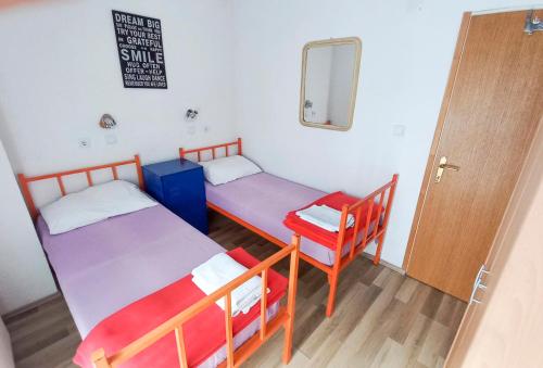 two beds in a room with a mirror and a door at Plitvice RH Hostel Rooms in Jezerce