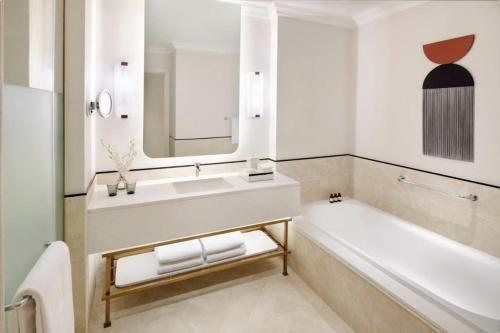 a bathroom with a tub and a sink and a mirror at Address Marassi Golf Resort Hotel Appartments in El Alamein