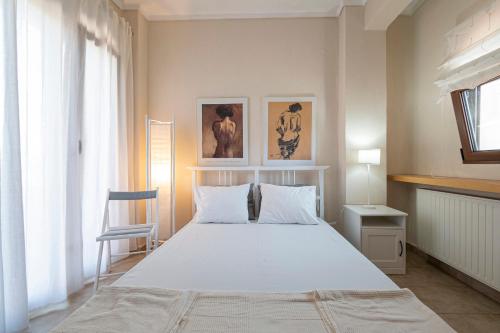 Un dormitorio con una gran cama blanca y una silla. en Alex & Billy House by Travel Pro Services - Nea Flogita Halkidiki, en Zográfos