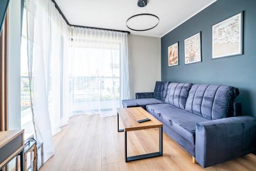 a living room with a blue couch and a table at Apartamenty i Pokoje Złote Piaski in Jastrzębia Góra