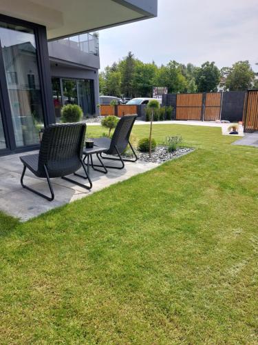 two chairs sitting on a lawn in front of a house at Apartamenty i Pokoje Złote Piaski in Jastrzębia Góra