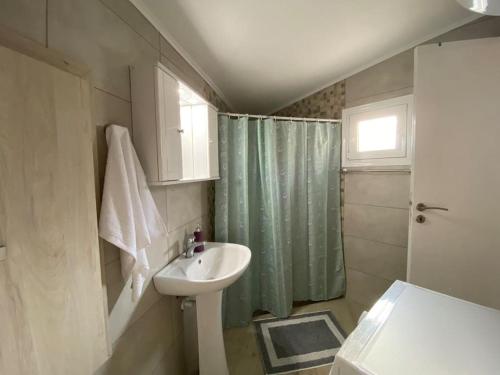 a bathroom with a sink and a green shower curtain at Asterion Bella View in Zaros
