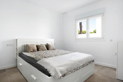 een witte slaapkamer met een wit bed en een raam bij Villa Santa Clara 21a in Chiclana de la Frontera
