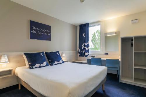 a bedroom with a large white bed with blue pillows at ACE Hôtel Thionville - Porte du Luxembourg in Thionville