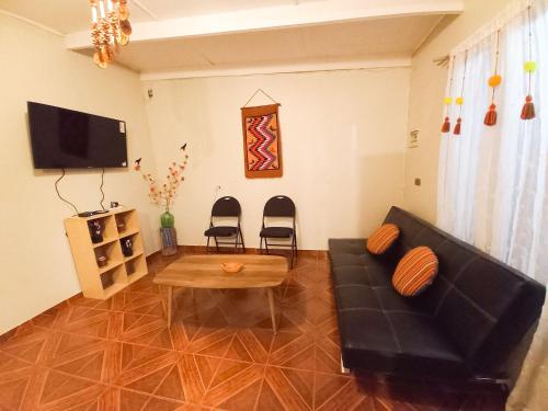 a living room with a black couch and a table at Casa Sutar Los Pimientos in San Pedro de Atacama