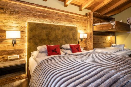 una camera con due letti in una stanza con pareti in legno di Dorfkrug Kaprun - Luxury Suites & Appartements by SFL a Kaprun