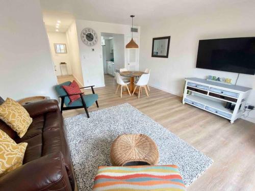 Sala de estar con sofá, TV y mesa en Endless Summer -Updated Townhome, 3-5 minute walk to the beach!, en Indian Harbour Beach