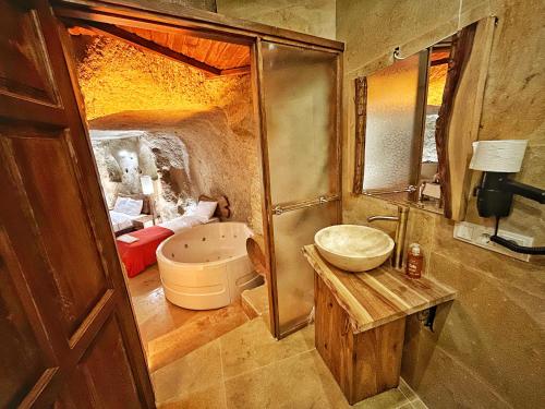 a bathroom with a sink and a tub and a mirror at Asma Altı Cave Suit's in Nar
