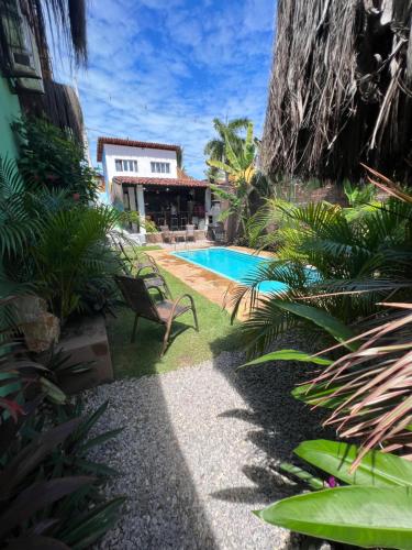 un patio trasero con piscina y una casa en Kuki's Hostel en Pipa