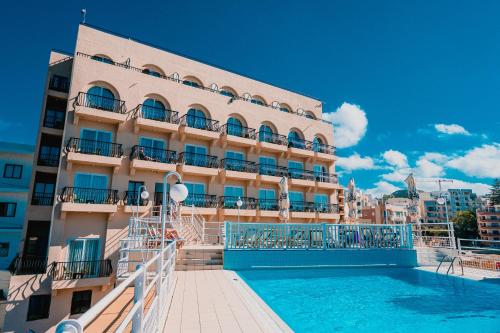 un hotel con piscina frente a un edificio en Gillieru Harbour Hotel en St Paul's Bay