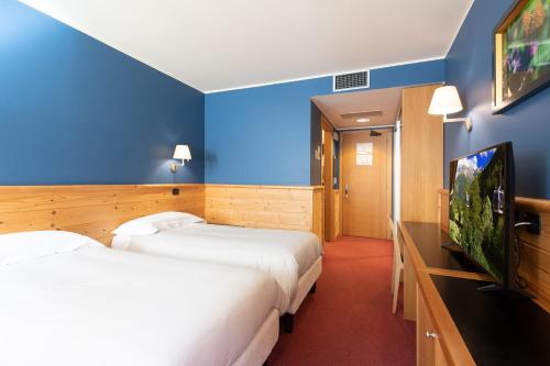 a hotel room with two beds and a flat screen tv at Hotel Garni Pegrà in Ponte di Legno