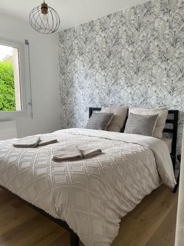 a bed in a white bedroom with a wall at Maison cosy avec jacuzzi in Néant-sur-Yvel