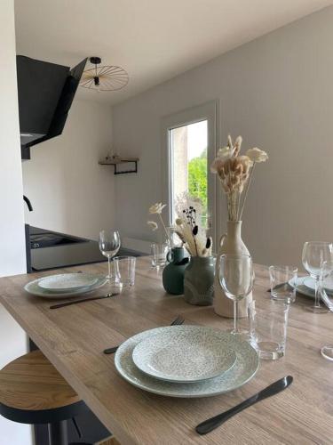 a wooden table with plates and glasses and a vase with flowers at Maison cosy avec jacuzzi in Néant-sur-Yvel