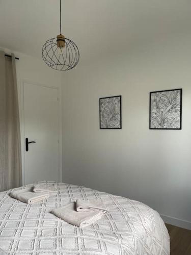 a white bedroom with a bed with three pictures on the wall at Maison cosy avec jacuzzi in Néant-sur-Yvel