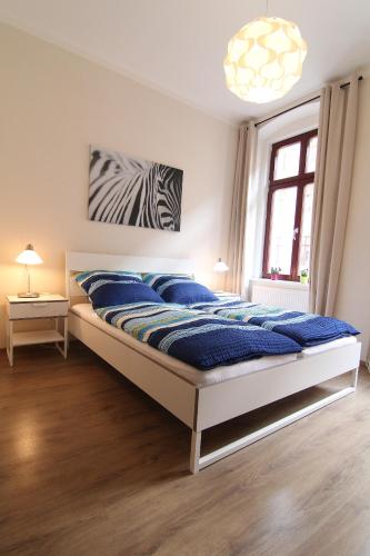 a bedroom with a bed with blue sheets and a zebra painting on the wall at Pension Alba in Görlitz