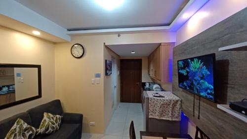 a living room with a couch and a tv on a wall at StayCation Dream CondoTel in Manila