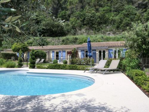 a swimming pool with two chairs and a house at Côté Lavande in Crestet