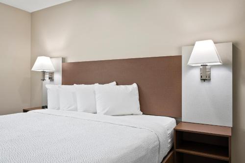 um quarto de hotel com uma cama com lençóis brancos e dois candeeiros em The English Inn of Charlottesville em Charlottesville