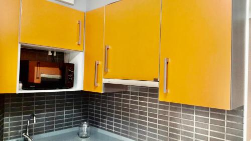 cocina con armarios amarillos y microondas en Apartamento Sol, en Gijón
