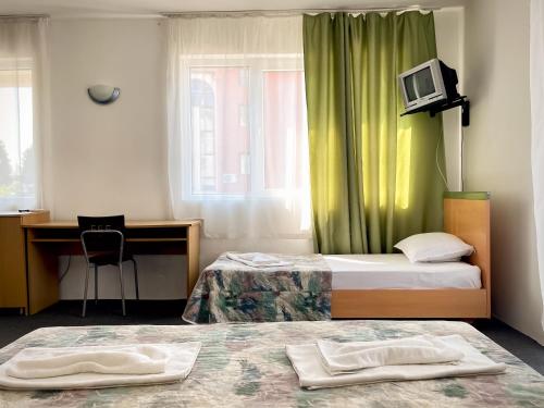 um quarto de hotel com duas camas e uma secretária e uma televisão em Mint Family Hotel em Ravda