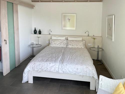 a white bed in a white bedroom with two tables at Almendro in Puntagorda