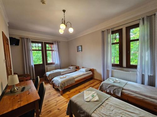 a room with three beds and a table and windows at Villa Alexandra in Polanica-Zdrój