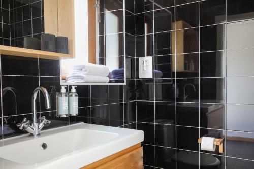 a black tiled bathroom with a sink and a mirror at Herdade da Matinha Country House & Restaurant in Cercal