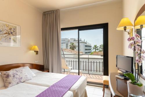 a hotel room with a bed and a balcony at Hotel Avenida in Tossa de Mar