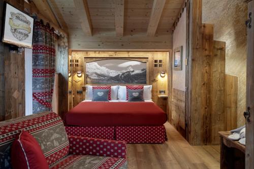 a bedroom with a red bed and a couch at Chalet Matterhorn Francois - Central Ski Chalet with SPA and Breakfast, 100mt lift in Breuil-Cervinia