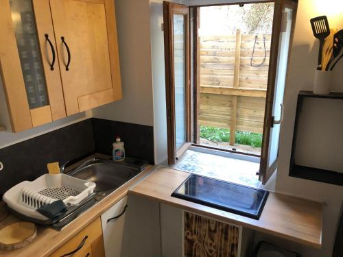 une petite cuisine avec un évier et une fenêtre dans l'établissement ORC Adventure - Les Monts du Lyonnais, à Vaugneray