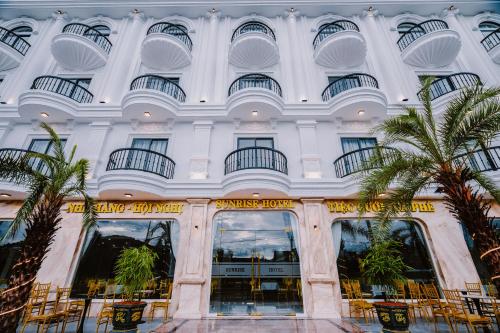 a building with palm trees in front of it at SUNRISE Hotel HA TIEN in Ha Tien