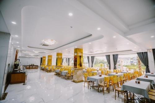 un salón de banquetes con mesas blancas y sillas amarillas en SUNRISE Hotel HA TIEN, en Hà Tiên